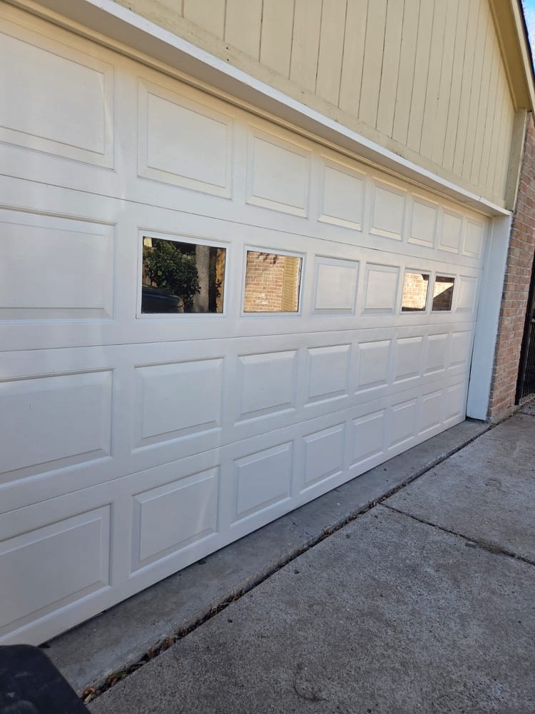 New white garage door with window inserts installed on a Houston home